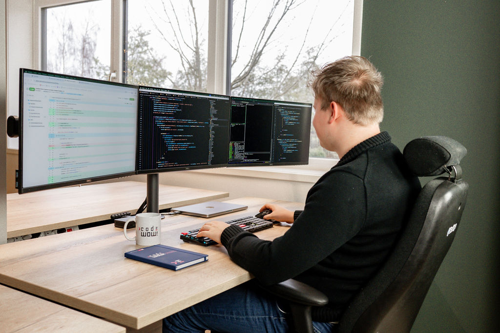 Collega die efficiënt werkt met drie schermen bij Code WOW!